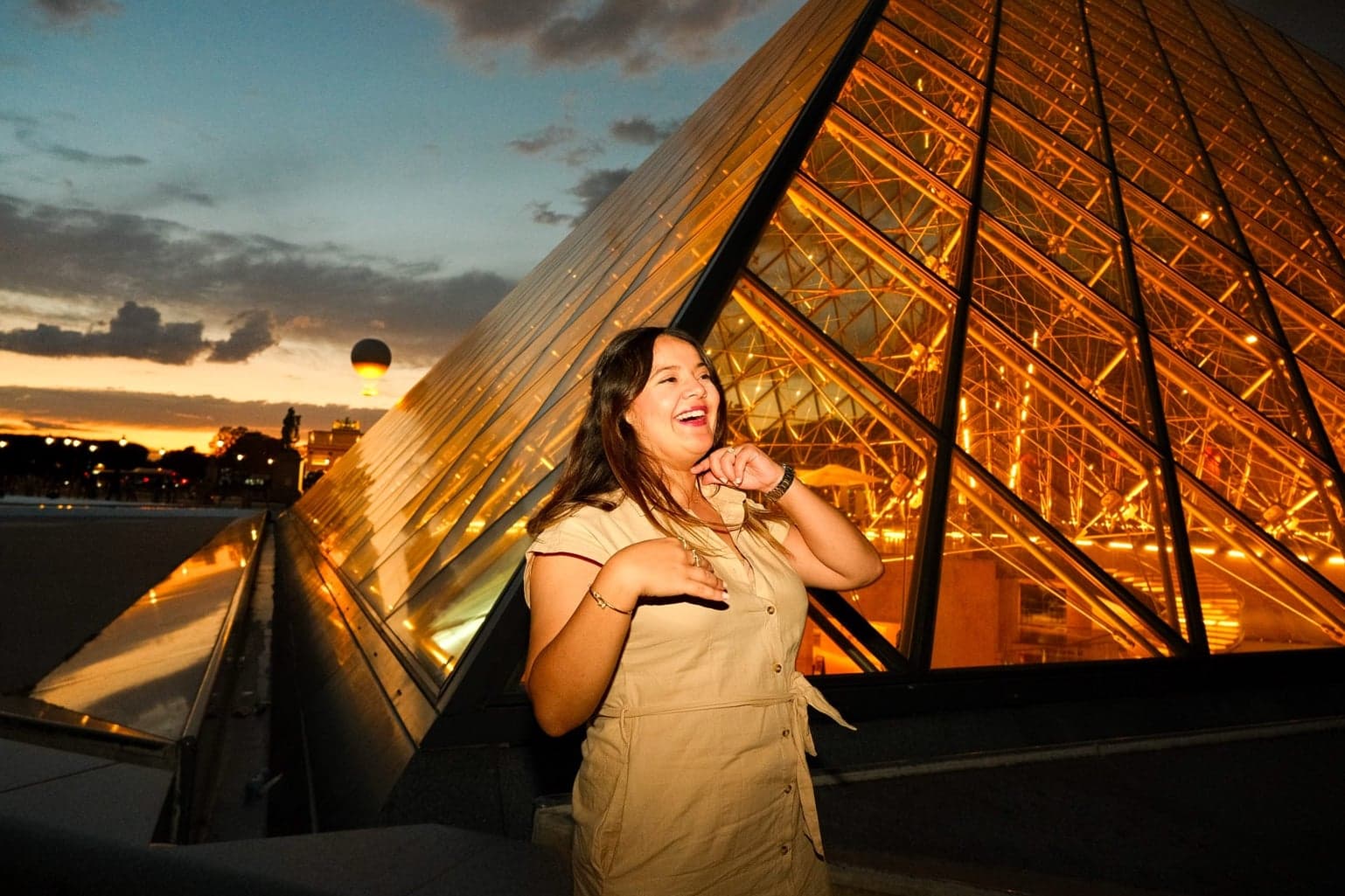 Woman beside the glowing Louvre Pyramid at golden sunset, an aesthetic instagrammable Paris photo spot by SabShots